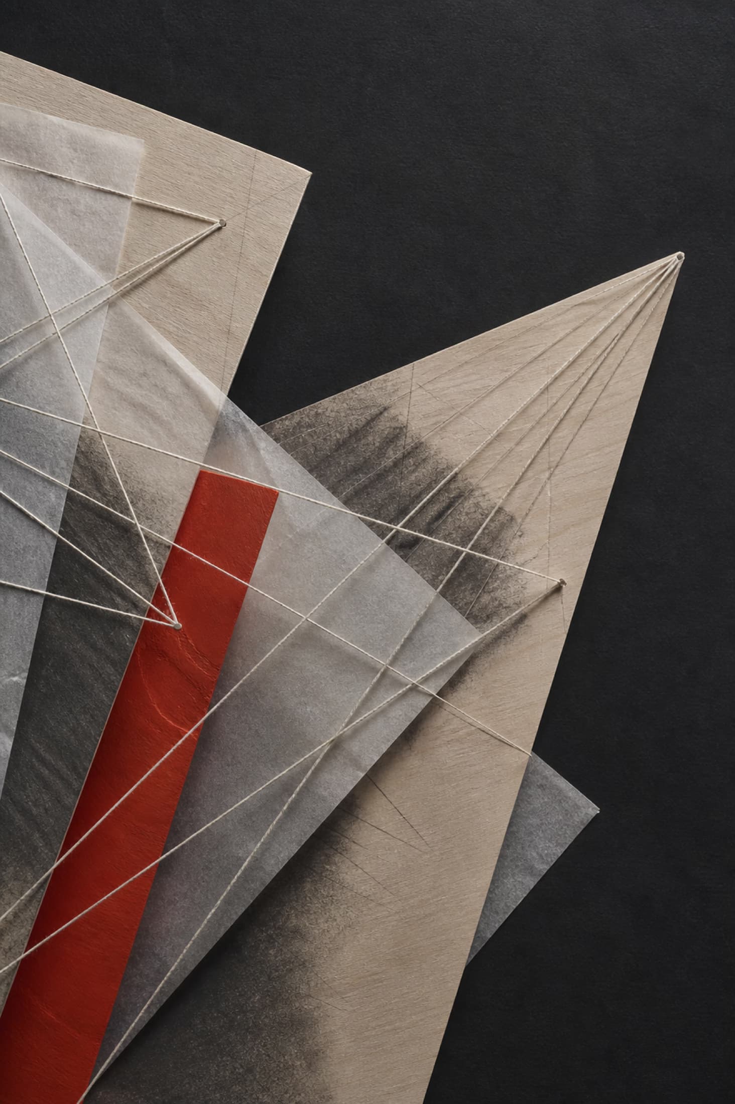 Abstrakte Materialstudie aus Holz, Graphit, Papier und Fäden mit einem roten Akzent